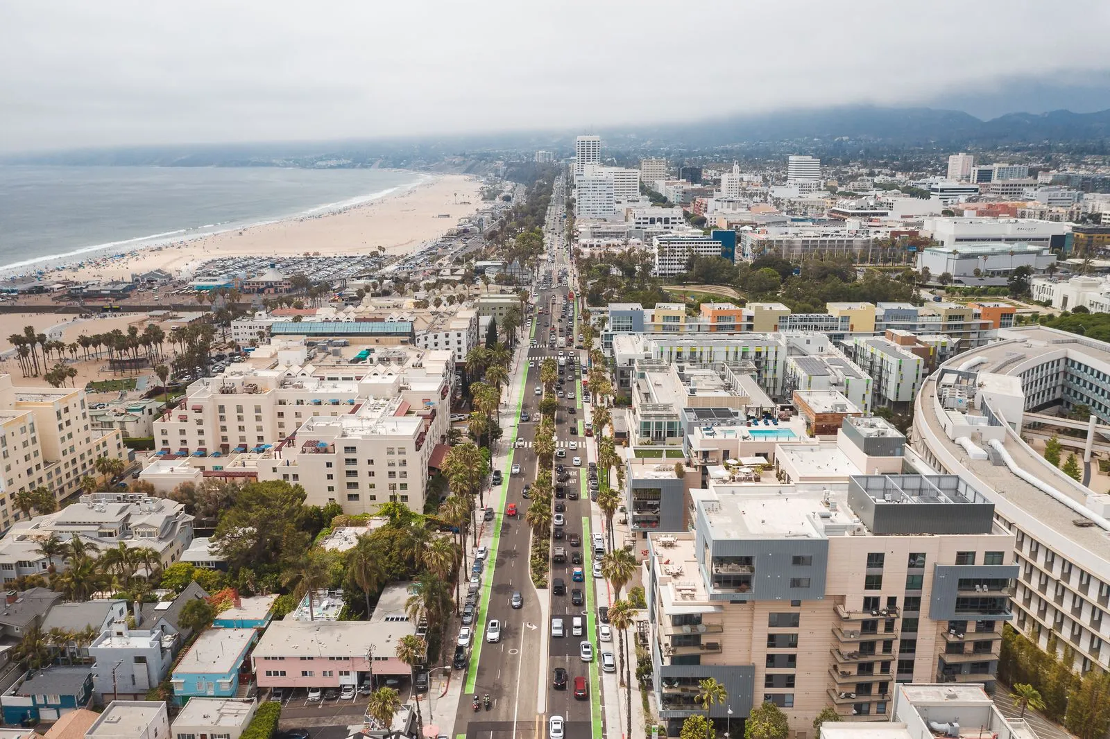 A breathtaking aerial view of Santa Monica's urban landscape, beach, and coastline under overcast skies.